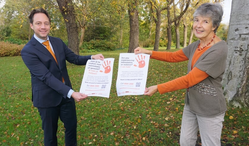 <p>Wethouder Paul de Bruijn neemt van Lineke Stoop de poster Stop Geweld tegen Vrouwen in ontvangst en toont met zijn oranje das zijn betrokkenheid bij deze belangrijke campagne. Foto: Vsk<br><br></p>