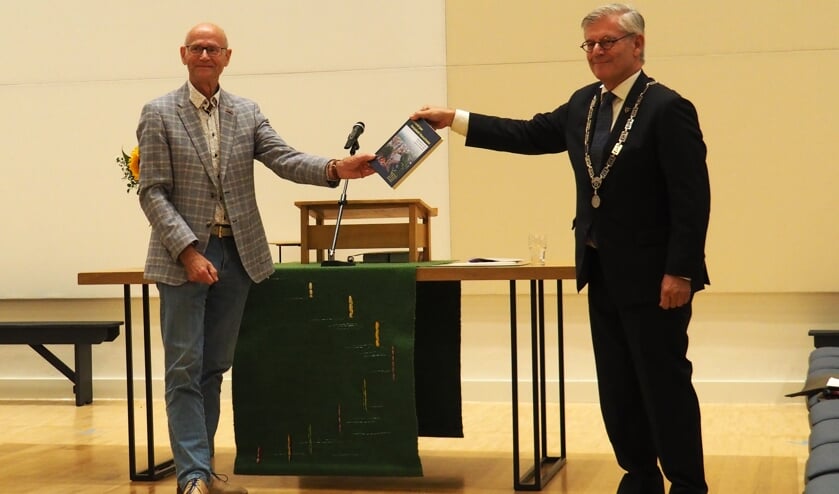 Burgemeester Aptroot krijgt het eerste exemplaar van '1000 jaar Dorpskerk' uitgereikt
