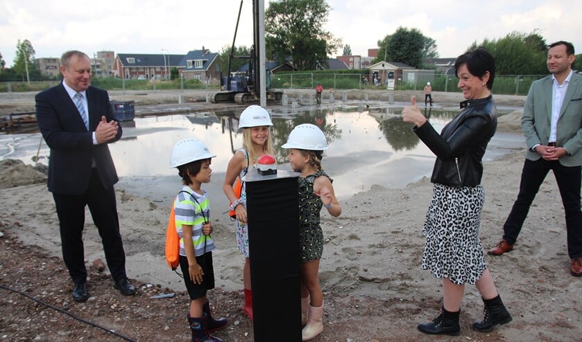 Fien, Fien en Abel hebben de eerste paal helpen slaan. De wethouder, de schooldirecteur en de bouwer zijn blij.