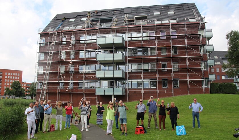 De bewoners heffen het glas terwijl achter hen op gevreesde hoogte het werk nog even doorgaat.