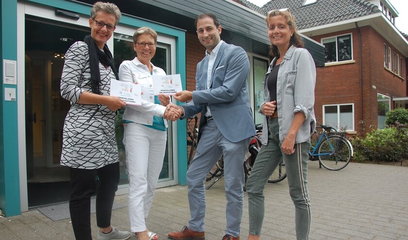 v.l.n.r. Nienke Oldenhuis en Francis Bennis bieden vol trots de informatieve folder over Mantelzorg aan huisarts Sander Gransjean en praktijkondersteuner Lilian Maas aan.
