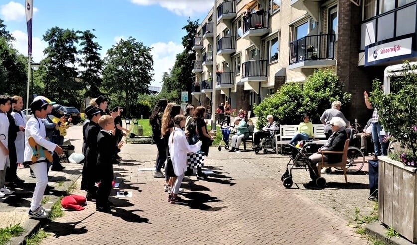 De basisschoolleerlingen voeren hun musical op voor de hoofdingang van WZH Schoorwijck (foto: Ap de Heus).