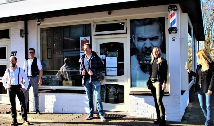 <p>Mark Rutte voor de deur van de kapsalon van Marco Rimmelzwaan (uiterst links) in Leidschendam (foto: VR Press).</p>