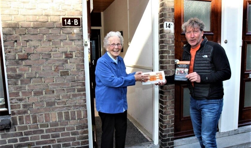 <p>Voorzitter Erik van der Linden overhandigt aan mevr. Zaat, één van de oudste leden van de vereniging, een doos met oranjetompoezen (foto Ap de Heus)</p>