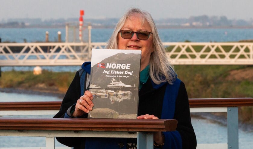 Cora de Boed met haar boek. Achter haar het Haringvliet. Foto: Leendert Verkerke