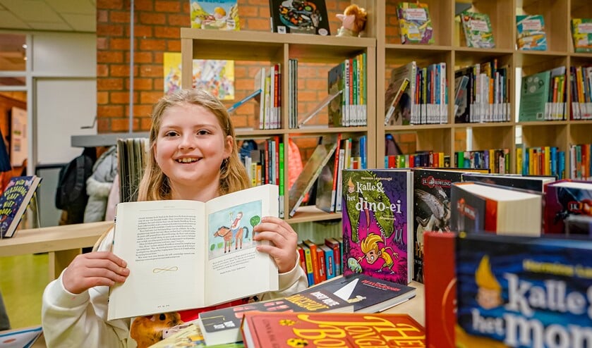 <p>Natalie Poolen laat, in de nieuwe schoolbibliotheek, trots haar tekening in het boek van J.K. Rowling zien. </p>