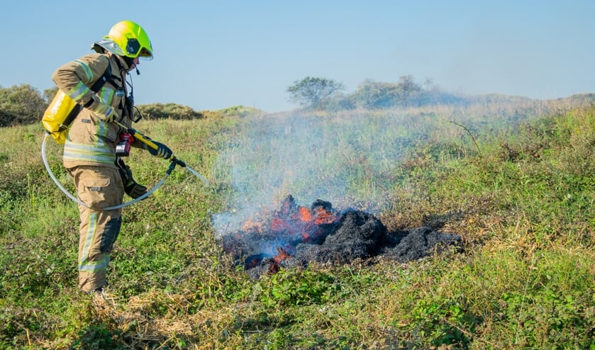 De brandweer gaat de duinen in met rugzakken vol water om zo verderop in het gebied te kunnen blussen. Foto: Sam Fish