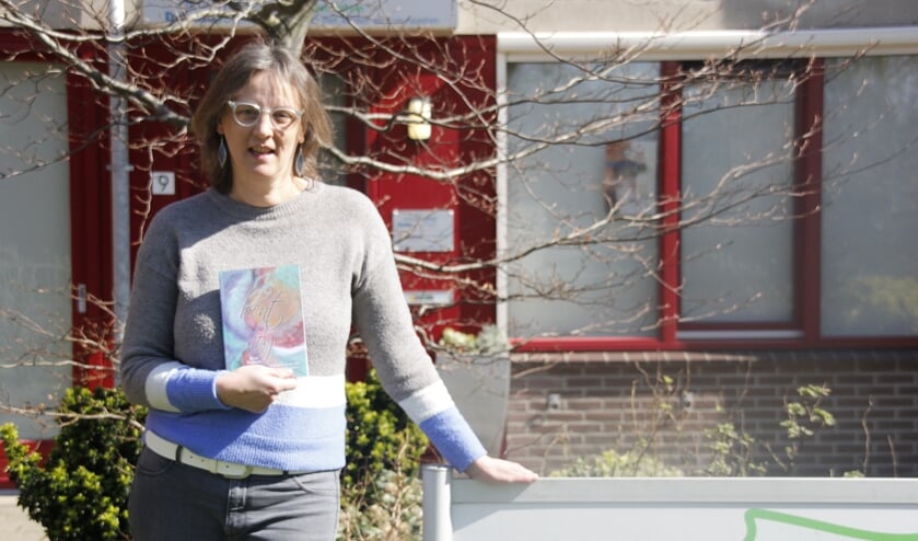 Anja Buurman (54), in haar hand haar gedichtenbundel 'Je bent er nog'.