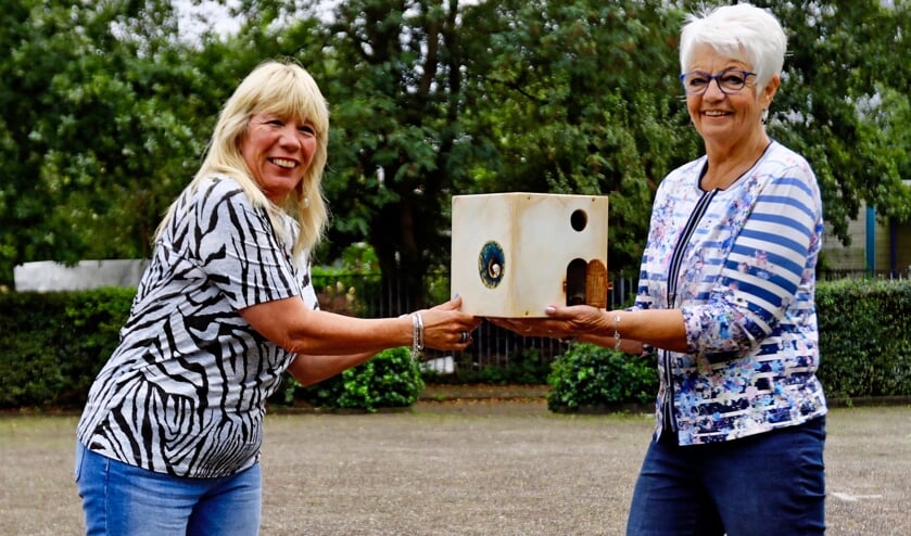 <p>Gerda Melema (r) draagt het kunstwerk over aan Ingrid Verwiel (l) bij de Vierhovenkerk, waar ISOFA - SchuldhulpMaatje Delft spreekuur heeft (Foto: Koos Bommelé)</p>