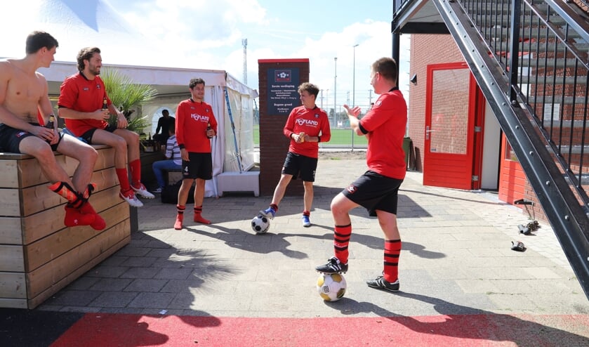 De spelers van het vierde drinken een biertje op afstand, als het weer verslechtert, kunnen ze dat in de tent doen.