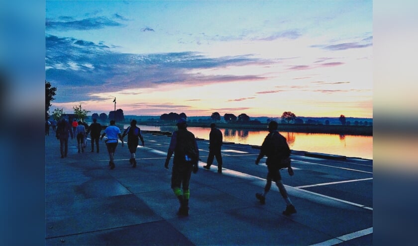 <p>Deelnemers aan 80 Land van Cuijk lopen in alle vroegste langs de Maas bij Cuijk. (foto: Robert Cooijmans)</p>