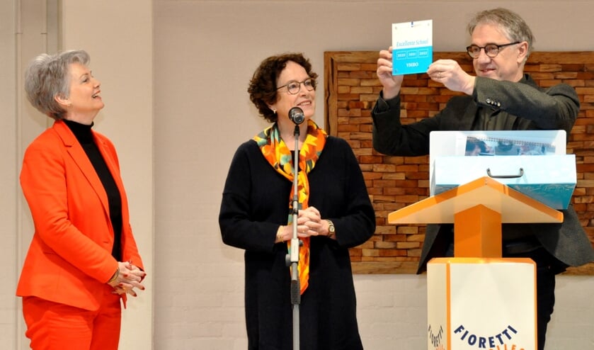 Anita (L) kijkt trots hoe Clemens Geenen van het Fioretti het predicaat in ontvangst neemt.