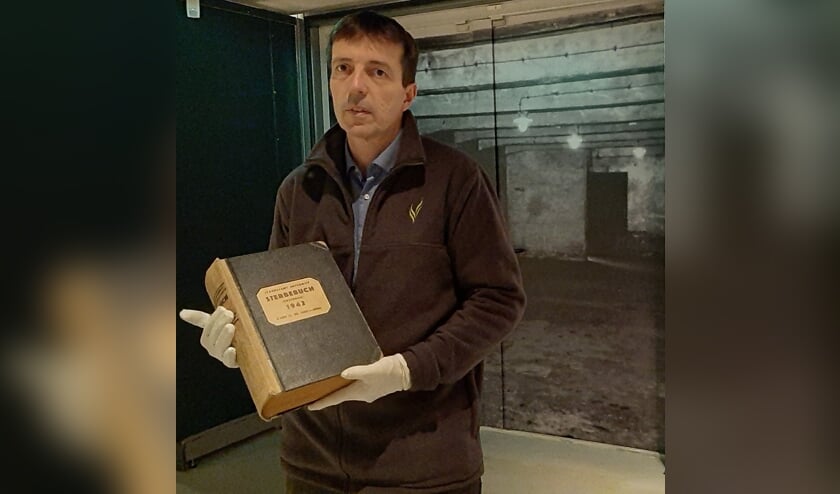 <p>De directeur van het Oorlogsmuseum in Overloon met het Dodenboek van Auschwitz.</p>