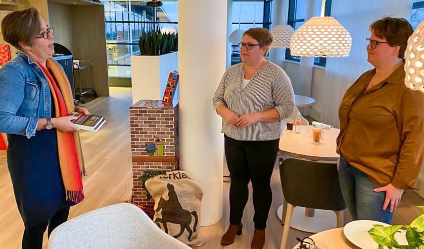 Lyan de Roos-Ro¨mkens overhandigt haar boek aan nabestaanden coronaslachtoffer.