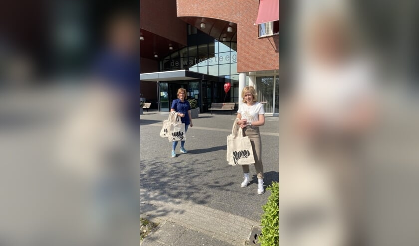 Diana van Dijk-Roelofs (r) overhandigt de Absolution verwentassen aan Wilma Vervoort (l) van de Watersteeg.
