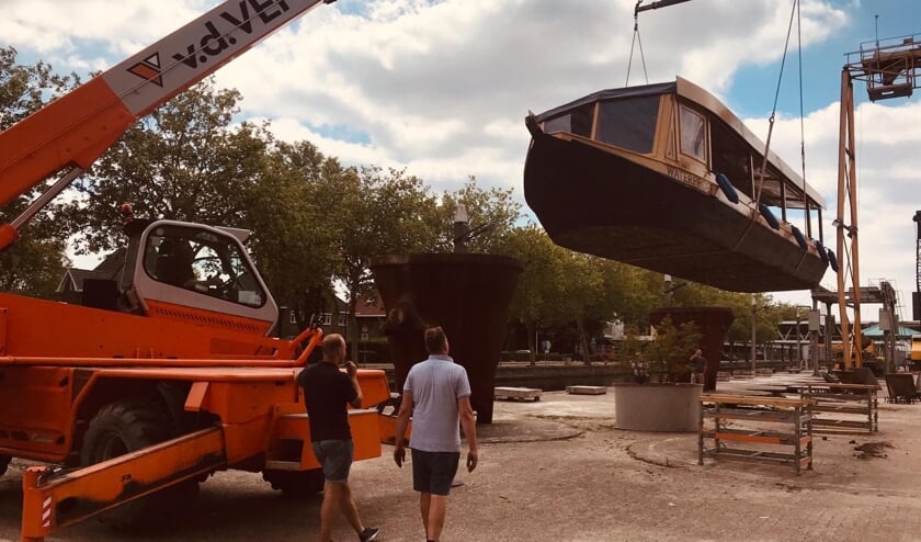 Martijn (rechts) kijkt toe hoe zijn rondvaartboot te water gaat.