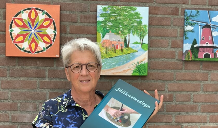 Diny Lamers met haar boek Schilderontmoetingen.