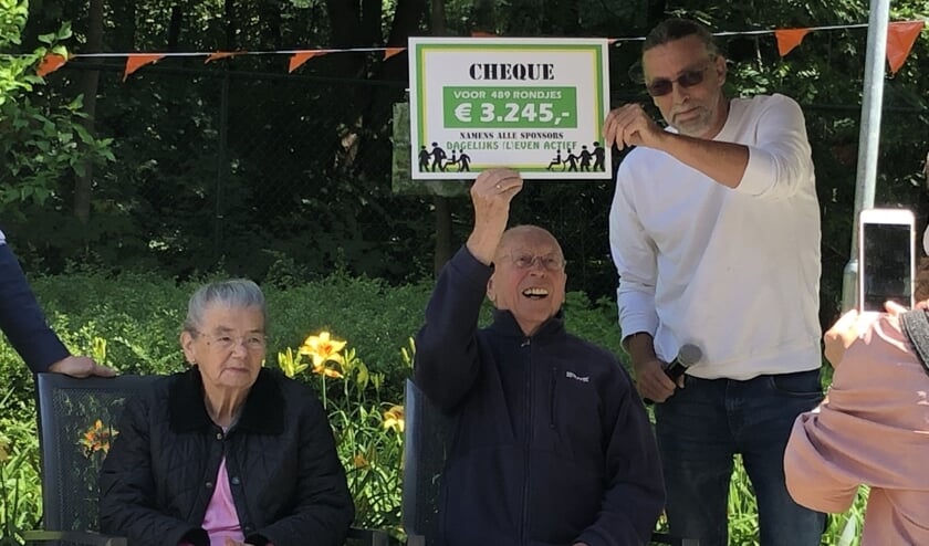 Jan Simons (94) steekt trots de cheque de hoogte in. Naast hem staat locatiemanager Rob Paulussen.