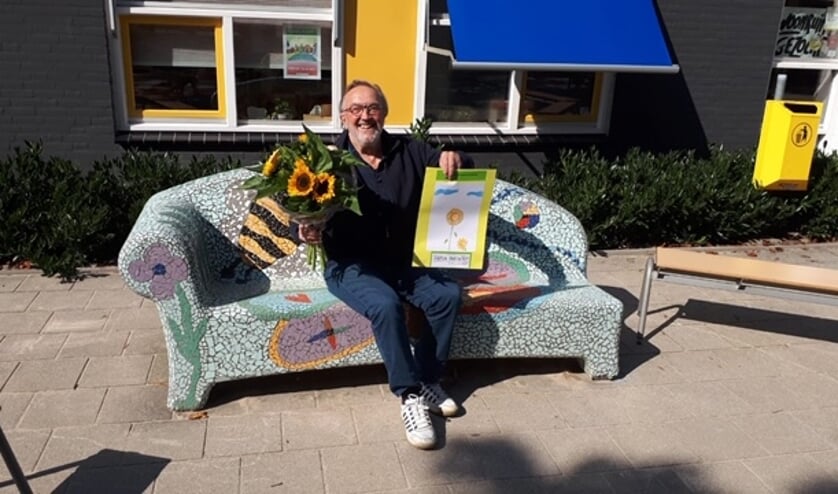 Een stralende winnaar op het bankje voor de school.