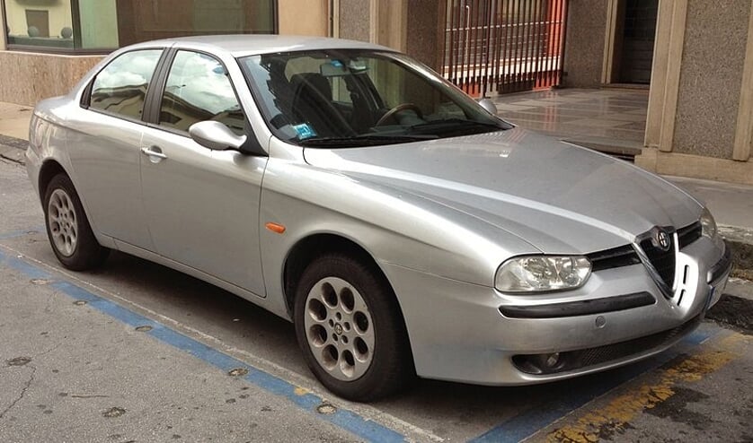 De vrouw rijdt rond in een blauw exemplaar van de hierboven afgebeelde Alfa Romeo 156 Berlina.