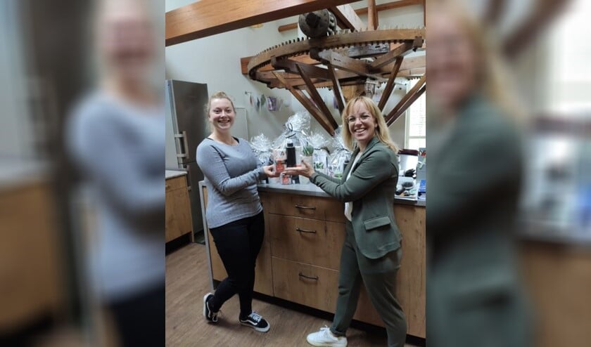 <p>Teamleider Femke de Bruijn (rechts) overhandigt het eerste pakket aan haar collega Celina.</p>