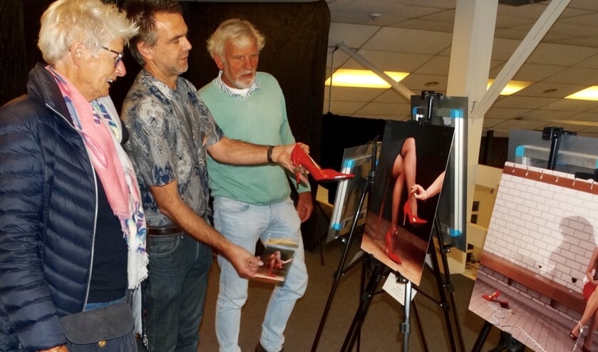 <p>In het midden Marc Olthoff, een van de initiatiefnemers van Kunstwerk te gast op een archieffoto. Hij toont een van zijn foto's aan trouwe bezoekers van de Kunstttoer 2019. </p>