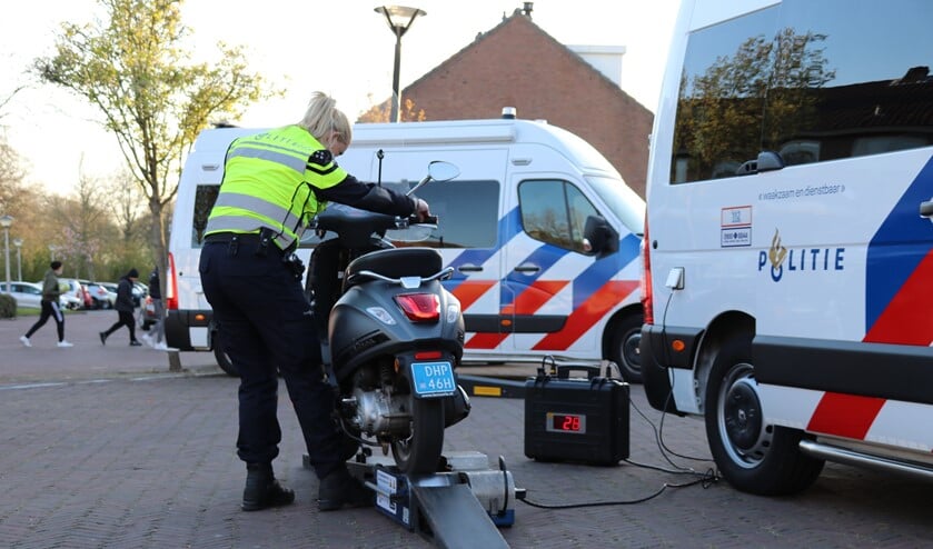 <p>Een agent controleert de maximum snelheid van een scooter op een zogenoemde rollerbank. (Foto: Spa Media)</p>