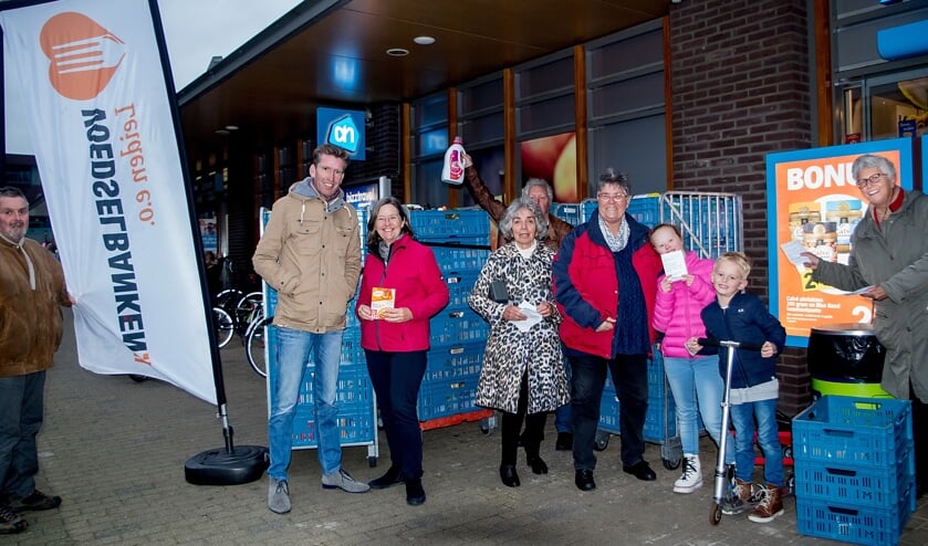 Vrijwilligers met blije gezichten na de inzameling voor de Voedselbank. Van links naar rechts: Jan Brouwer de Koning, Heleen Feenstra, Evelien Mieremet, Ellis Groothoff, twee geïnteresseerde kinderen en Wil Schenk. In de achterhoede – met wasmiddel - Cor Los van de Voedselbank. | Foto: J.P. Kranenburg