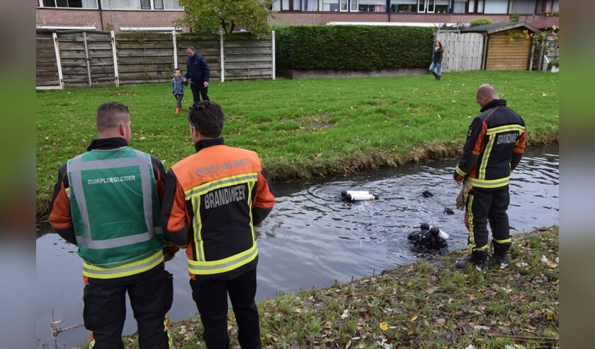 Duikers zoeken in de sloot naast het tankstation naar het bij de overval gebruikte mes.