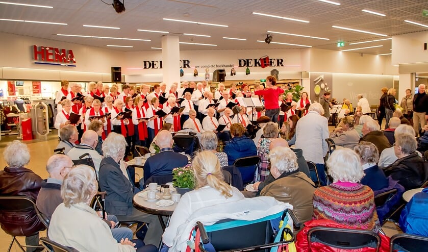 De ouderen komen even bij van het winkelen met een kop koffie plus een taartje en zang van het koor Young@Heart.