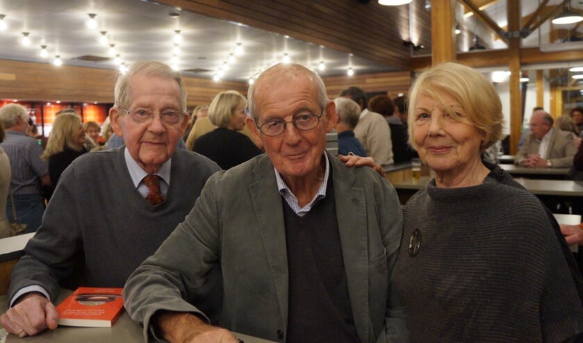 Har Meijer (midden) signeert een boek voor twee dorpsgenoten.