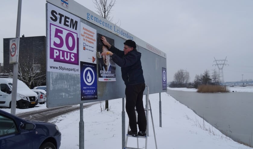 Jan Meijles plakte zondag de GroenLinks posters op de verkiezingsborden.