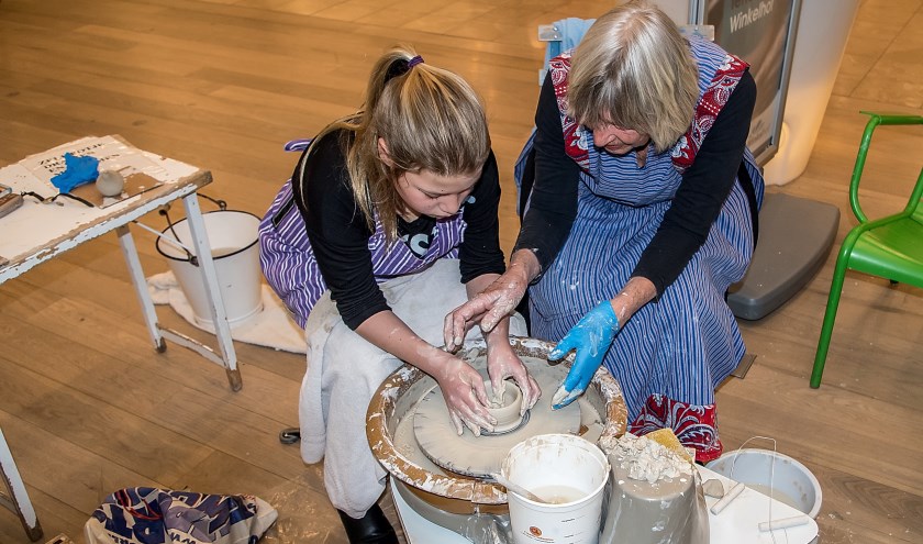 Een jonge bezoekster van Winkelhof krijgt een lesje pottenbakken.