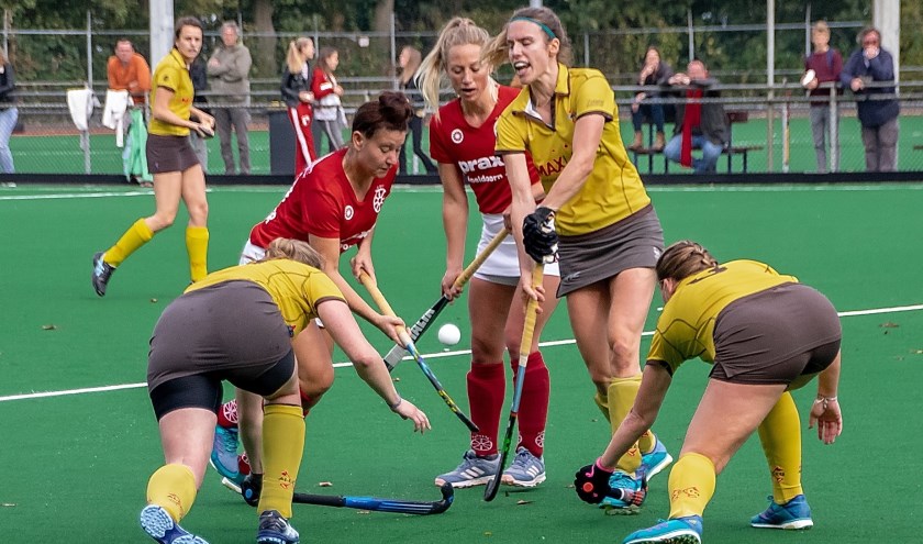 Gevecht om de bal. Rechtop staat Rose Breedveld, links en rechts staan gebukt respectievelijk Rosanne Pries en Mathilde Dezitter.