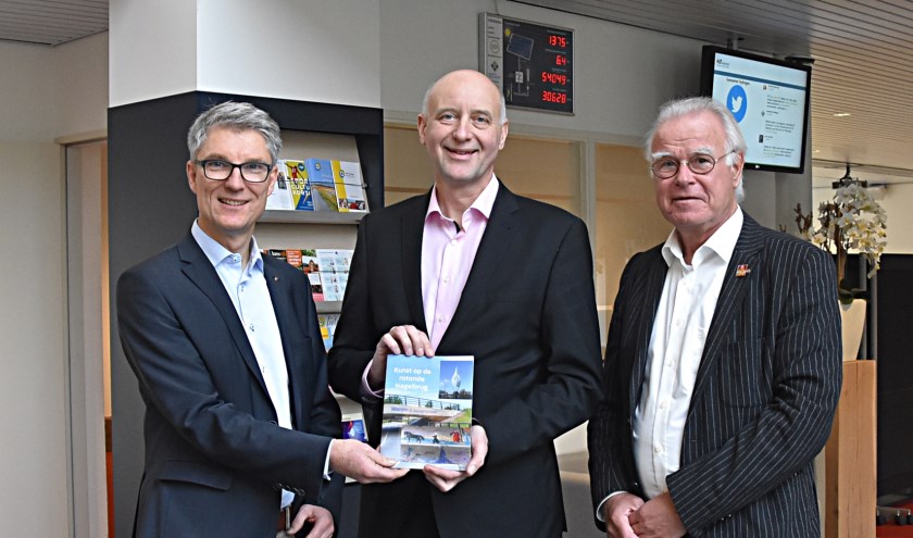 Nic van Tilborg (l.) en Siebe Stellingwerff Beintema overhandigen het boekje aan wethouder Arno van Kempen. | Foto: Piet van Kampen