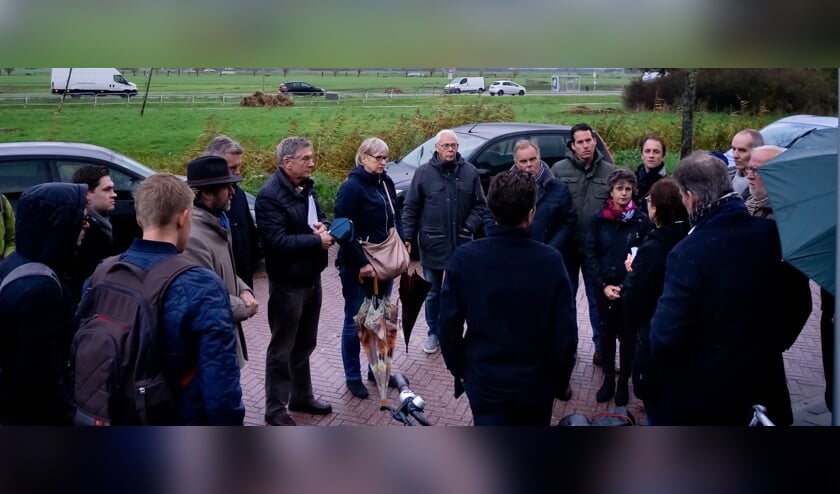 Raadleden, omwonenden en gemeenteambtenaren aan de Dijkwacht. Op de achtergrond de Oude Spoorbaan waarlangs dranghekken zijn gezet die de hoogte van de beoogde geluidsschermen weergeven.