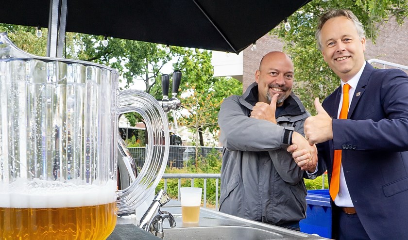 Wethouder Willem Joosten van duurzaamheid (rechts) heeft net de eerste een eco-pitcher bier getapt en schudt de hand van Nico de Bruin van Grand Café Hofplein, die het experiment met de ecoglazen coördineert.