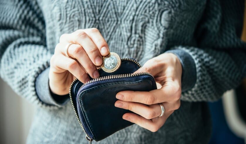 <p>Hands holding british pound coin and small money pouch</p>