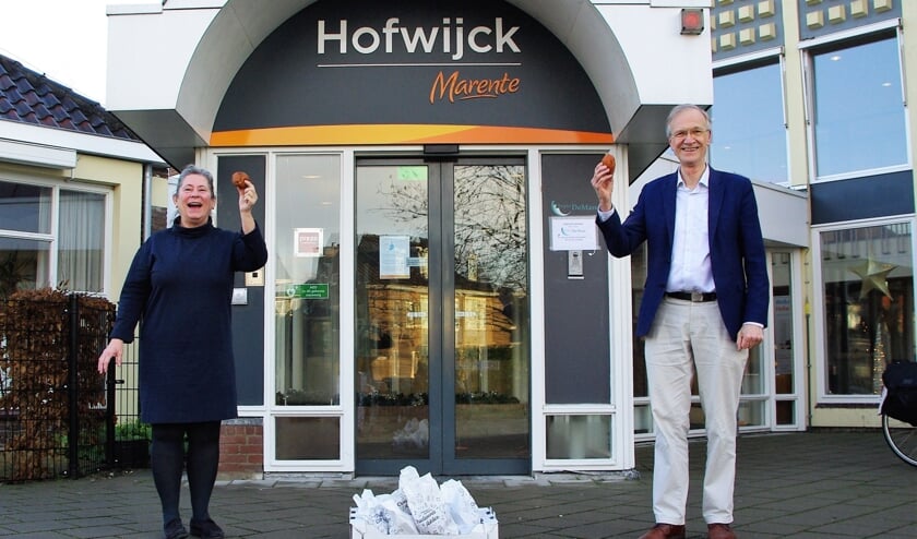 <p>Locatiemanager Renate Claassen van Hofwijck nam blij de oliebollen in ontvangst van wethouder Jan Nieuwenhuis. | Foto Willemien Timmers</p>