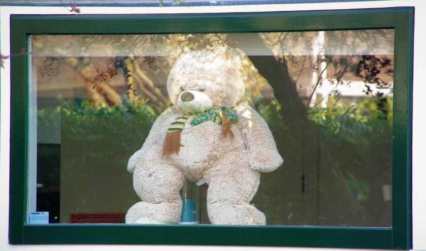 Een knuffelbeer kijkt nieuwsgierig naar buiten of er al kinderen langs wandelen. |