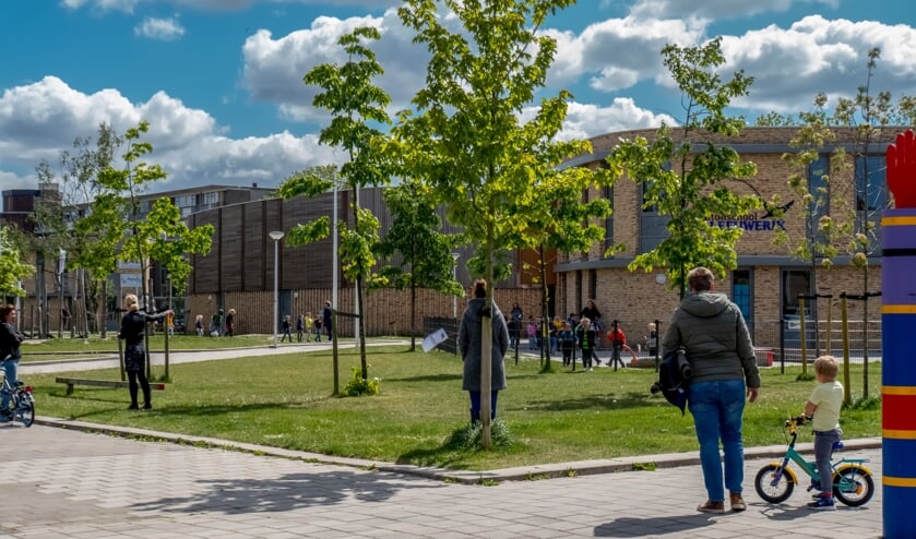 Ouders staan, netjes buiten het schoolplein, te wachten op hun kinderen bij De Leeuwerik.