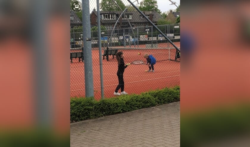 Lisa Schouten op de tennisbaan. De foto is gemaakt door haar moeder die door het hek van een afstandje mocht toekijken.