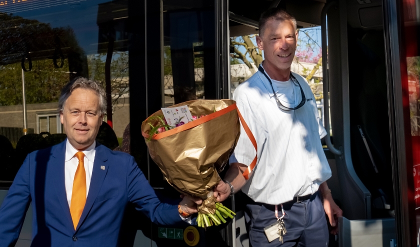 Verkeerswethouder Willem Joosten (VVD) overhandigt een bos bloemen aan buschauffeur Johan Spek.
