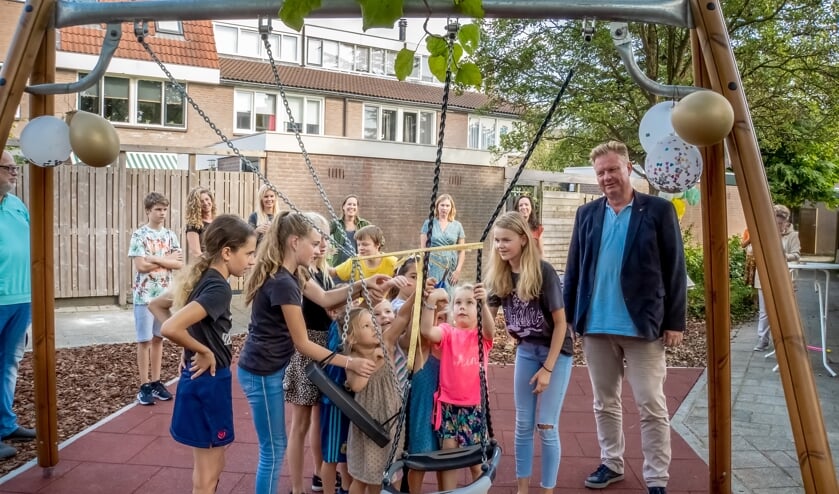 Wethouder Rik van Woudenberg kijkt toe hoe kinderen uit de buurt hun speeltuin openen.