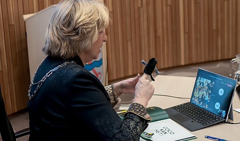 <p>Burgemeester Driessen, met Coco-vingerpoppetje, achter haar laptop waarop ze haar jonge publiek ziet.</p>