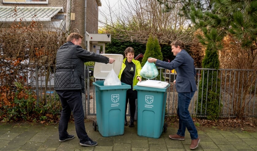 <p>Wethouder Rik van Woudenberg (links) en GroenLInks fractievoorzitter Bob Vastenhoud gooien onder toeziend oog van Petra Kappetein van De Dartel zakken met luiers in de inzamelbakken. </p>