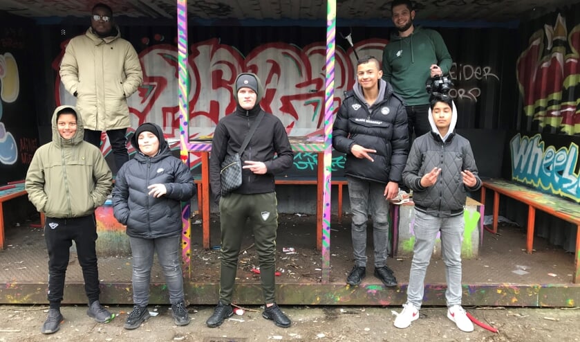 <p>Een aantal van de jongeren die meededen aan de rapworkshop met achter hen rappers GIDO (links) en Nick.</p>