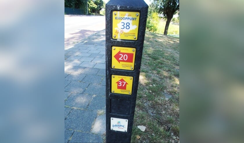 Een wandelknooppunt met het nummer van de paal en pijltjes naar de volgende knooppunten.