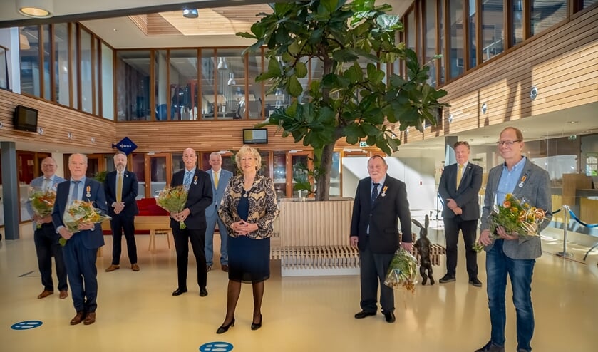 <p>De gedecoreerden (met bloemen) en het Leiderdorpse college van B en W. V.l.n.r. Gerrit Anker, Rob Snoep, wethouder Willem Joosten, Jos van der Lubbe, wethouder Daan Binnendijk, burgemeester Laila Driessen, Willem Molenaar, wethouder Rik van Woudenberg en Ed Weijdeveld. | Foto: J.P. Kranenburg</p>