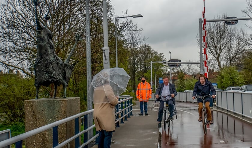 <p>Wethouder Rik van Woudenberg (links) en gedeputeerde Floor Vermeulen fietsen de Stierenbrug op, waar burgemeester Laila Driessen hen opwacht bij de stier. Er was niet toevallig gekozen voor de fiets: Van Woudenberg zou graag zien dat Leidenaren en andere regiobewoners Leiderdorp te fiets bezoeken. </p>